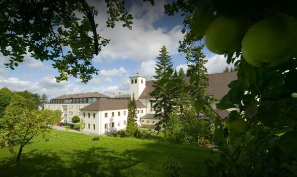 A large building with a prominent tower, surrounded by lush greenery and trees.
