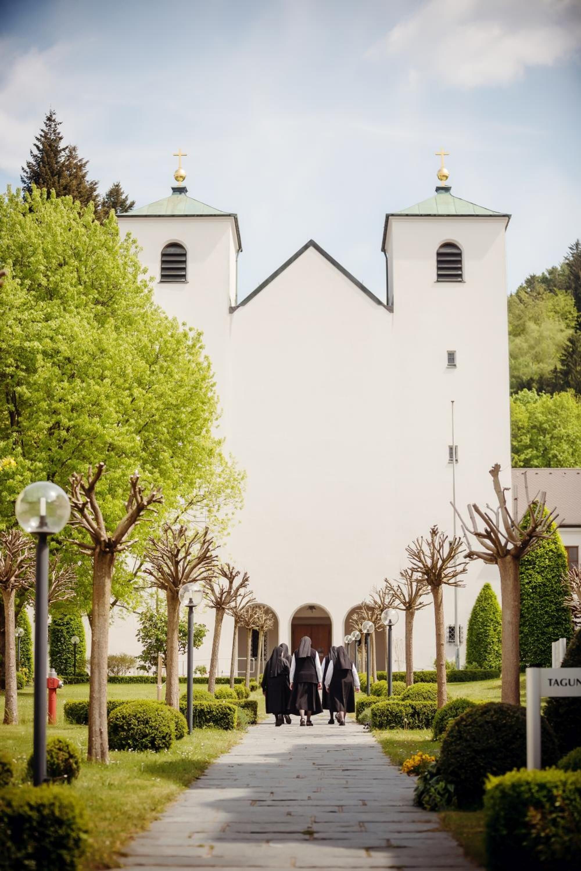 Un sendero que lleva a una iglesia con dos torres y una cruz en la parte superior.