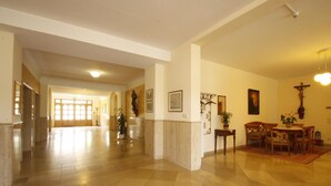 A spacious lobby with a marble floor, a reception desk, and a dining area with wooden furniture.