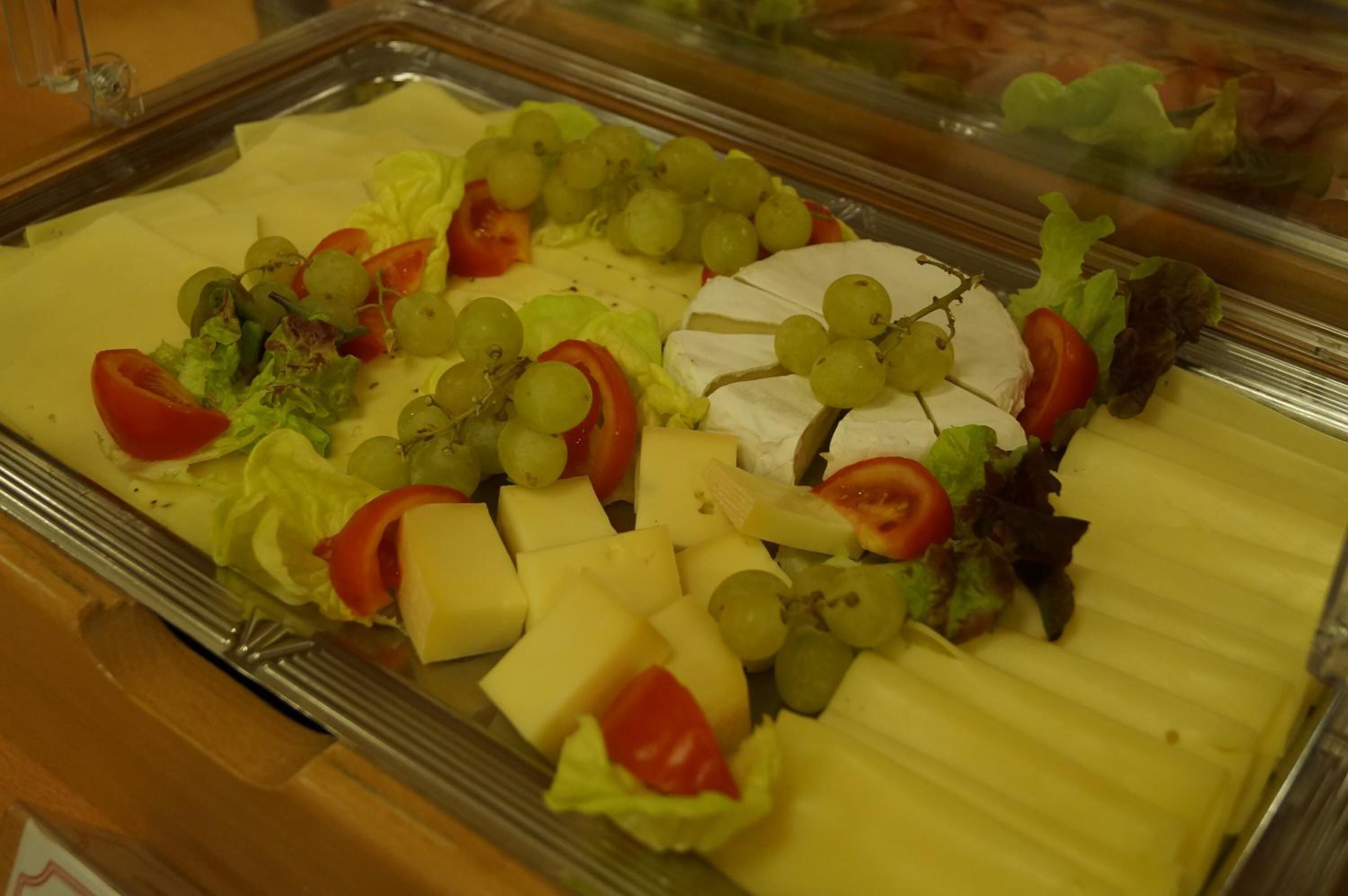 A buffet with various cheeses, fruits, and vegetables.