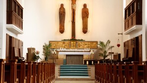 A church interior with wooden pews, a crucifix, and a pulpit.