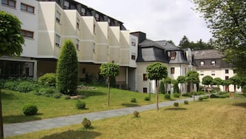 A modern building with multiple floors, a paved pathway, and well-maintained greenery.