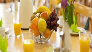 A breakfast table with a fruit bowl, a pitcher, and glasses of orange juice.