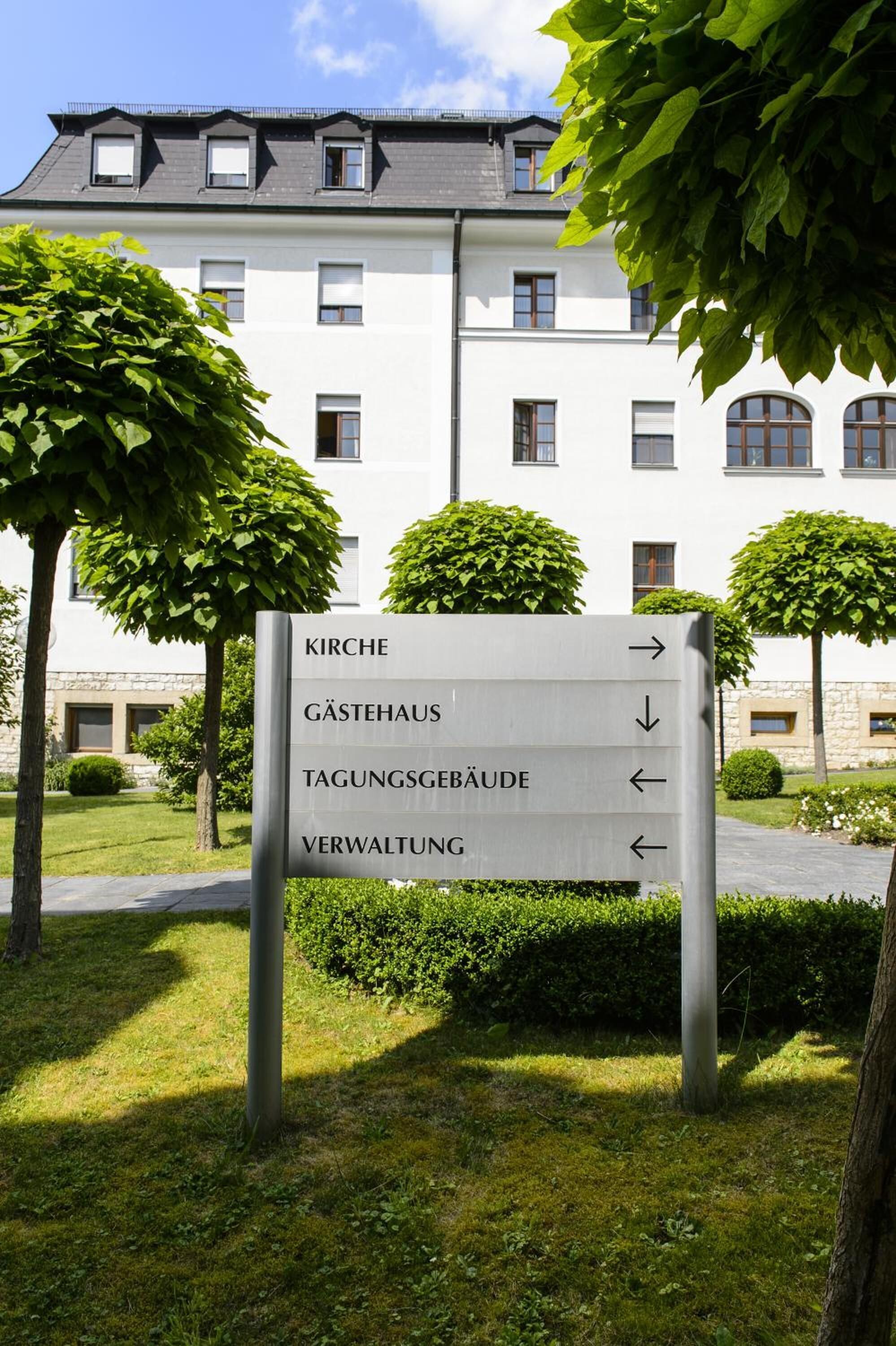 A directional sign with arrows pointing to different parts of a building.