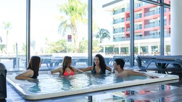 Un grupo de personas en un jacuzzi con vistas a un edificio y palmeras.