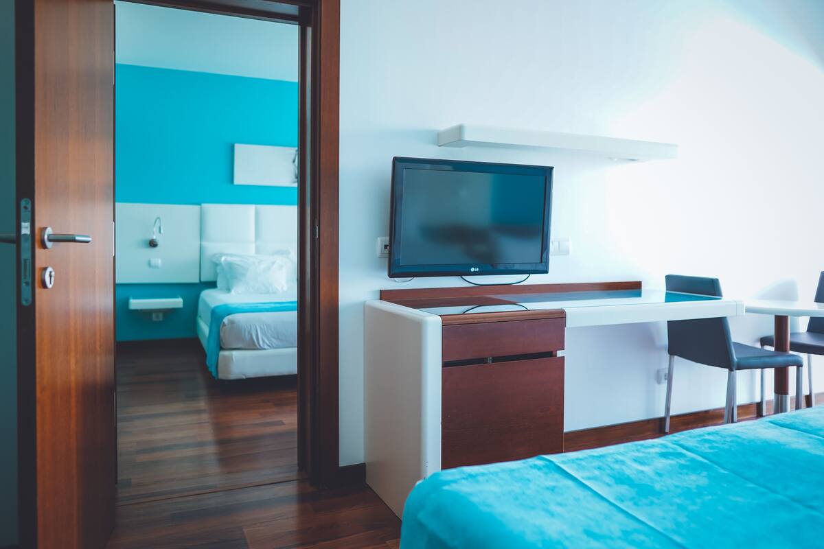 Hotelkamer met een bed, bureau, stoel, televisie en een badkamer op de achtergrond.
