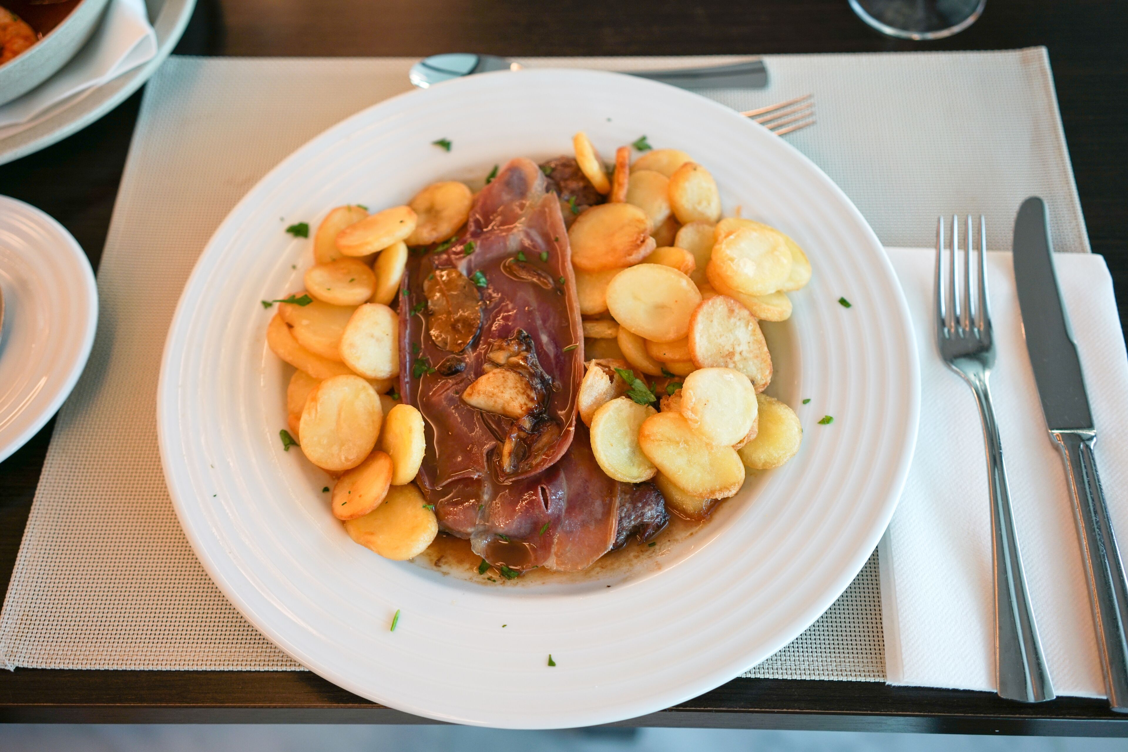 A plate of food with a large piece of meat and potatoes.