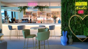 Zona de bar con un letrero de neón que dice "COCKTAILS & Dreams" y una decoración con forma de corazón en una pared verde.