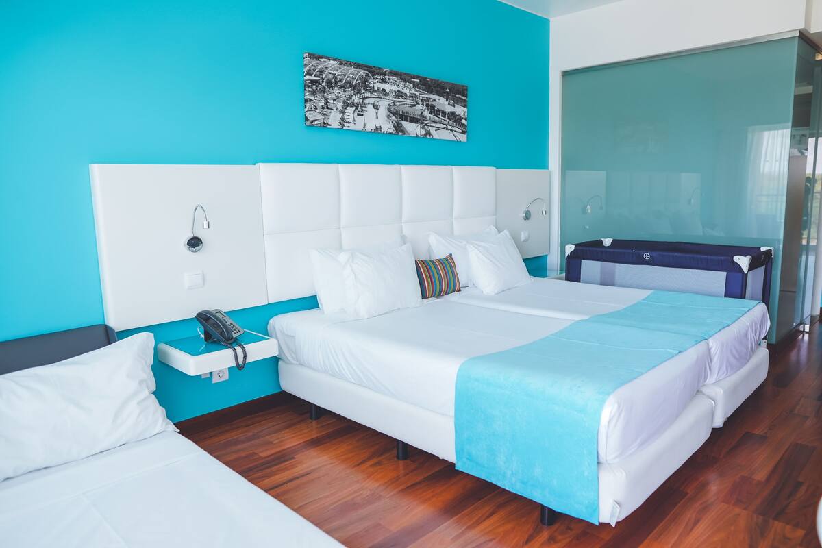 Een moderne hotelkamer met een groot bed, een nachtkastje met telefoon en een blauwe accentmuur.