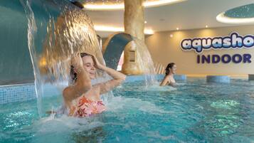 An indoor swimming pool with water features and a sign for 'aquasho INDOOR'.