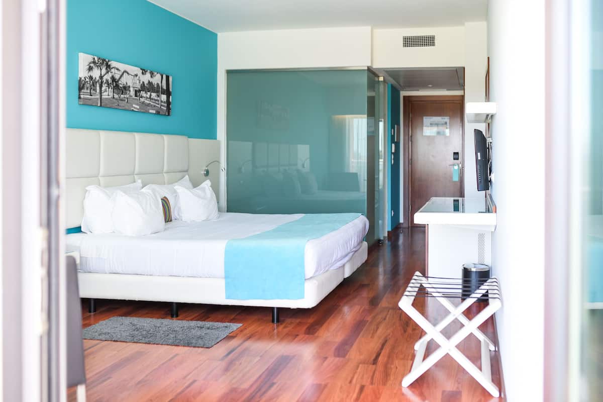 Een hotelkamer met een bed, een bureau en uitzicht door een glazen deur.