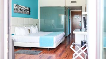 Habitación de hotel con cama, escritorio y vista a través de una puerta de cristal.