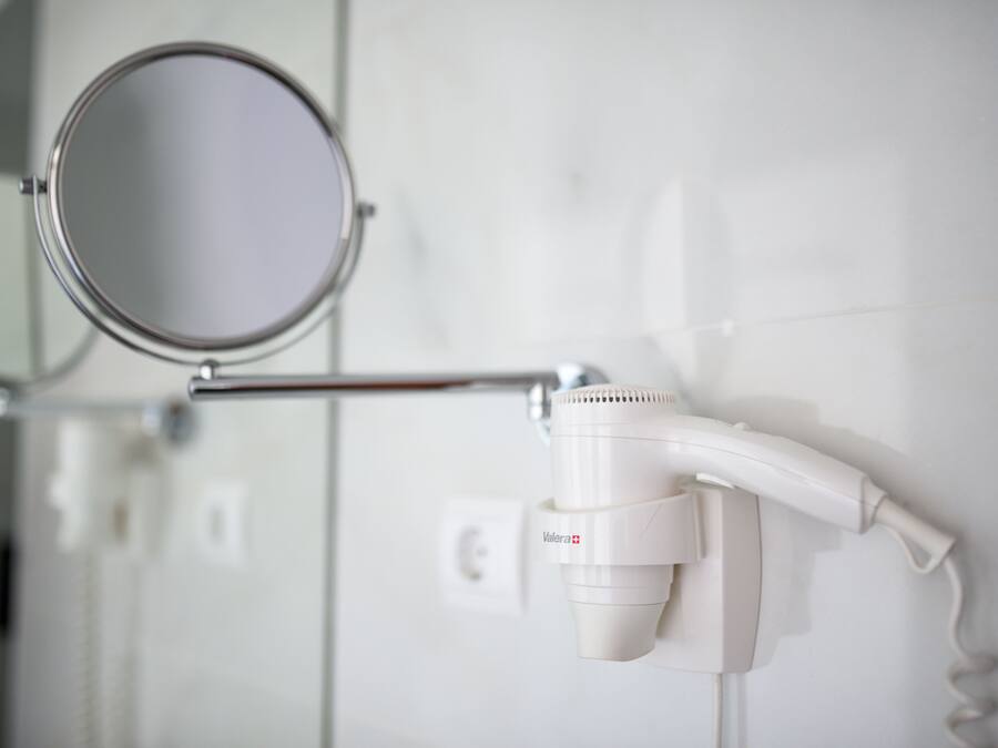 A bathroom with a mirror, a hairdryer, and a towel rack.