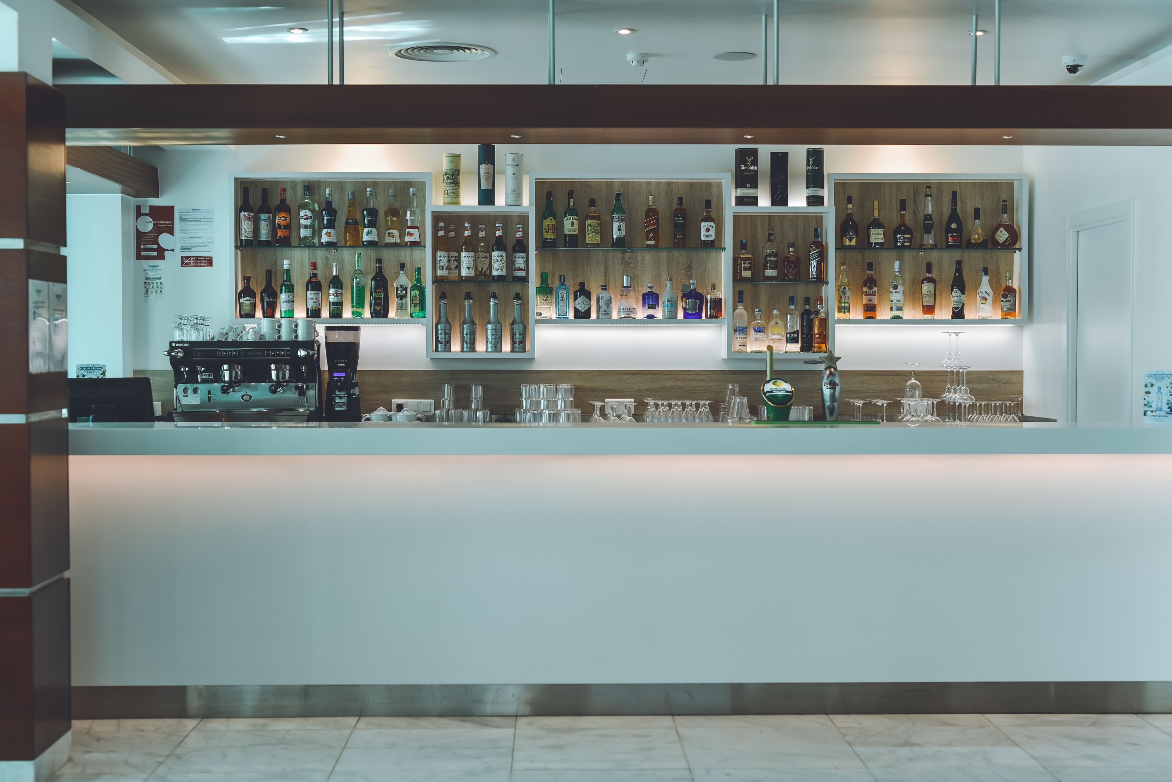 A bar area with shelves of liquor bottles, a coffee machine, and a bar counter.