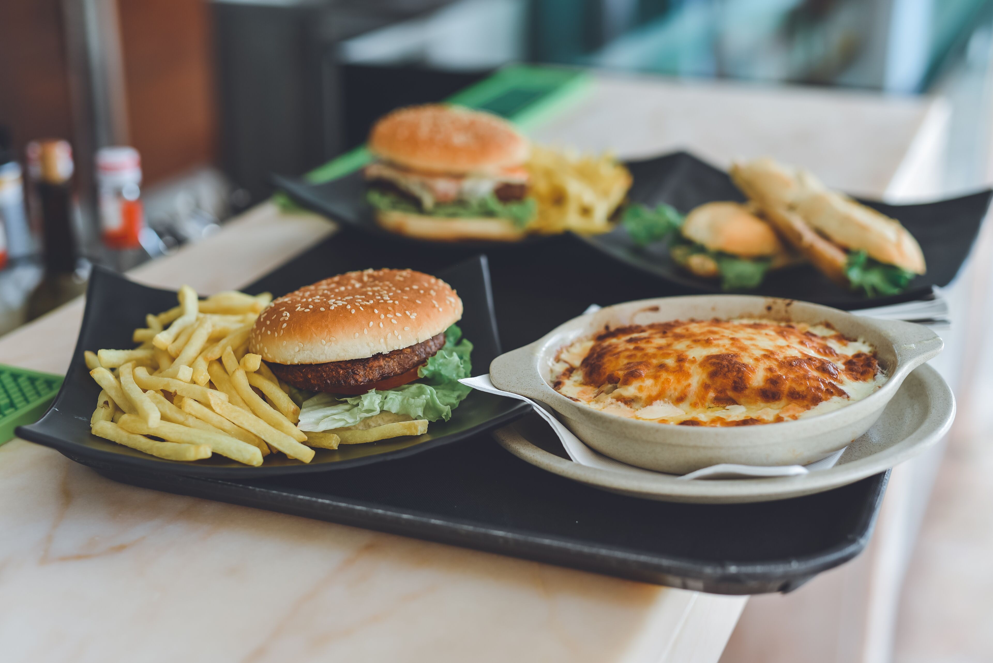 A tray with a burger, fries, and a baked dish.