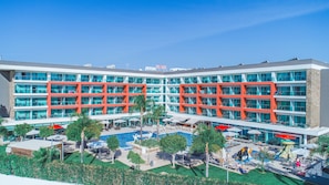 A multi-story hotel with a pool area, outdoor seating, and a view of the surrounding landscape.