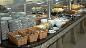 A buffet with various food items and stacked plates. - Hotel Dan Inn Express Foz do Iguaçu By Nacional Inn (Foz do Iguaçu)