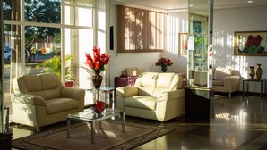 A spacious living room with two beige sofas, a glass coffee table, and a large window providing a view of the outdoors. - Hotel Dan Inn Express Foz do Iguaçu By Nacional Inn (Foz do Iguaçu)