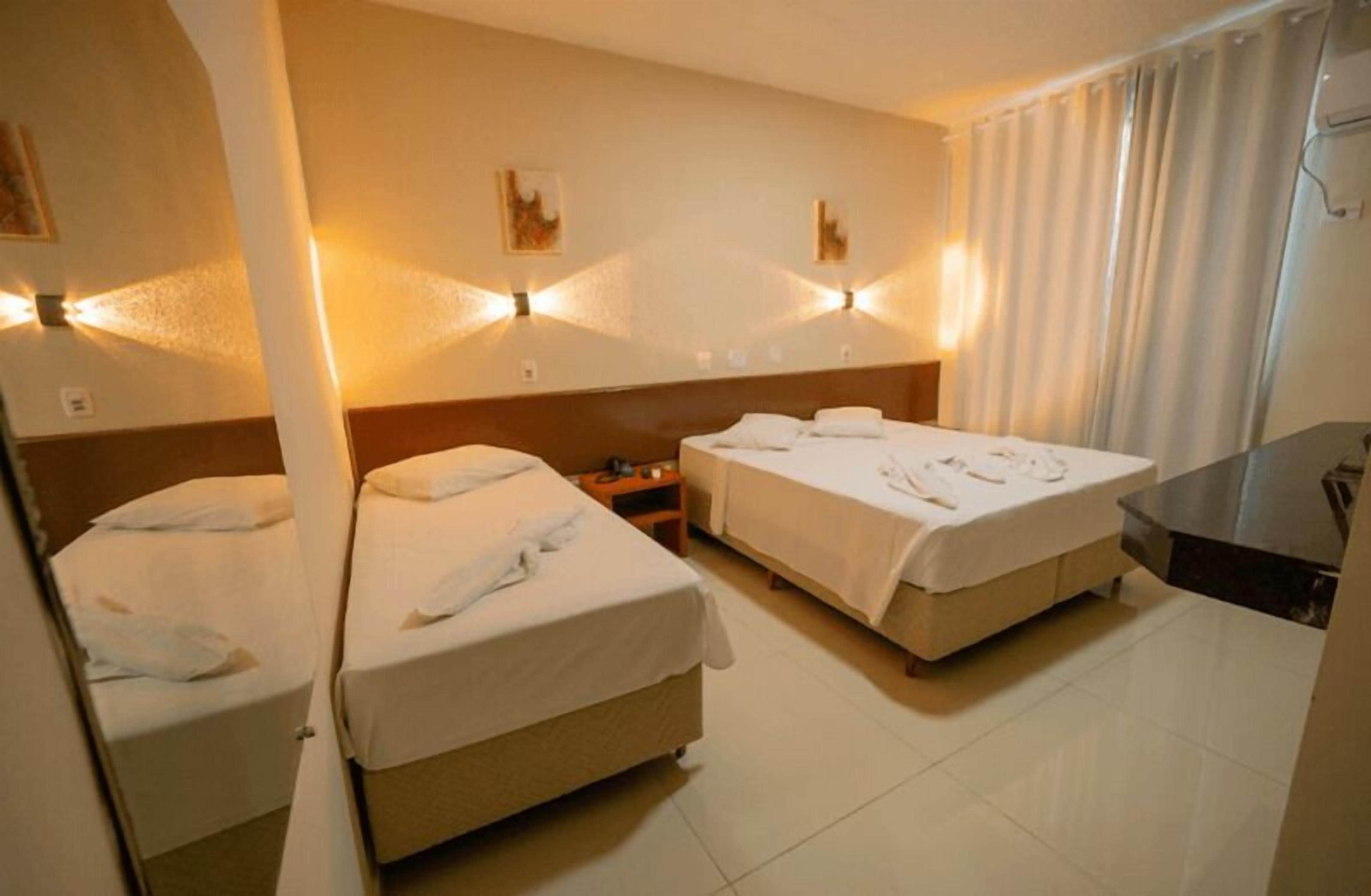 Een hotelkamer met twee bedden, een bureau en een badkamer.