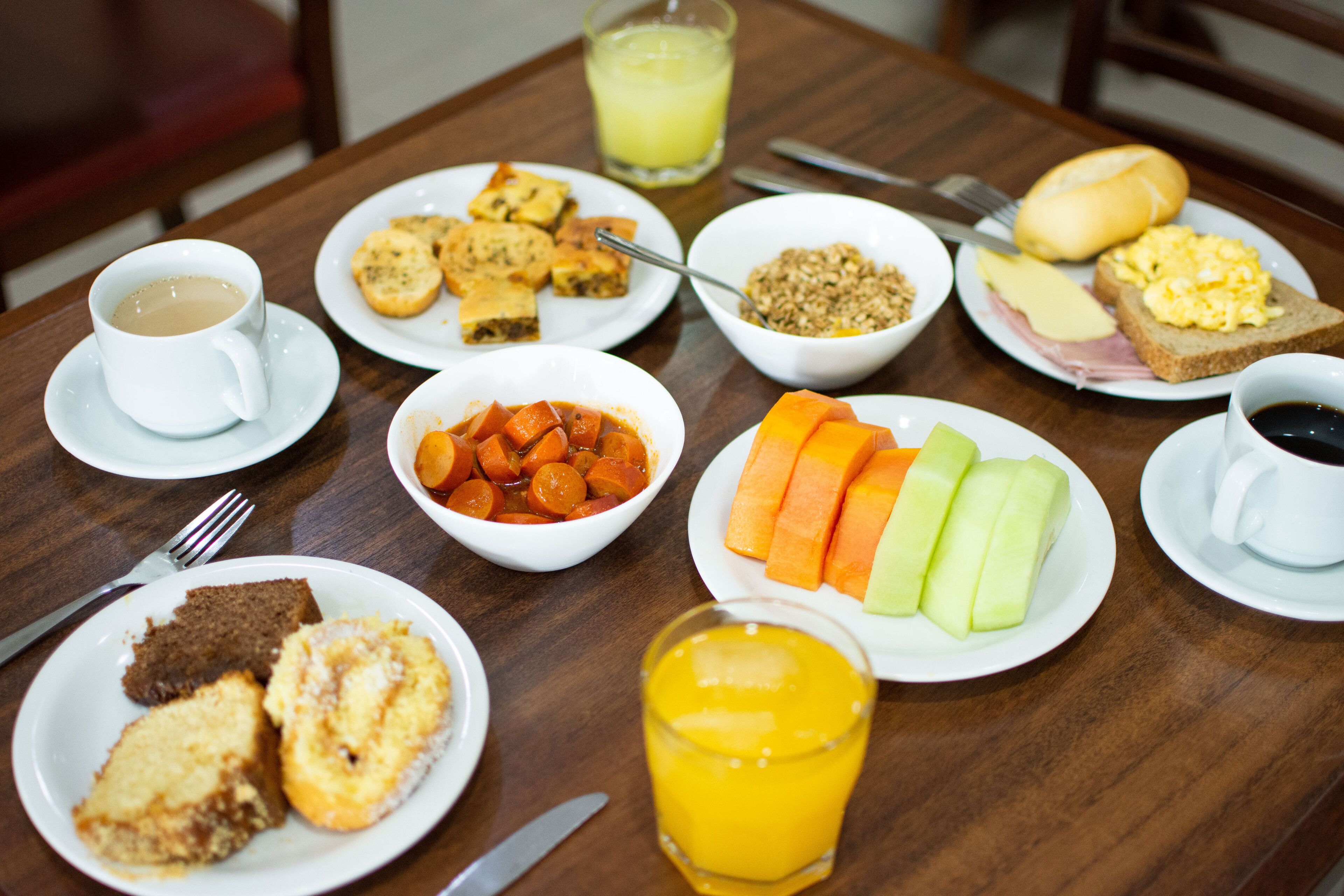 Una mesa de desayuno con diversos platos, incluyendo tostadas, huevos y fruta.
