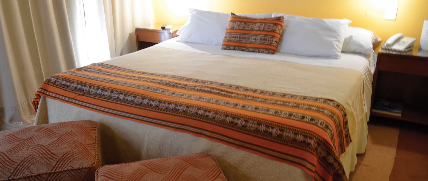 Une chambre d’hôtel avec un grand lit, une table de chevet avec une lampe et un téléphone.