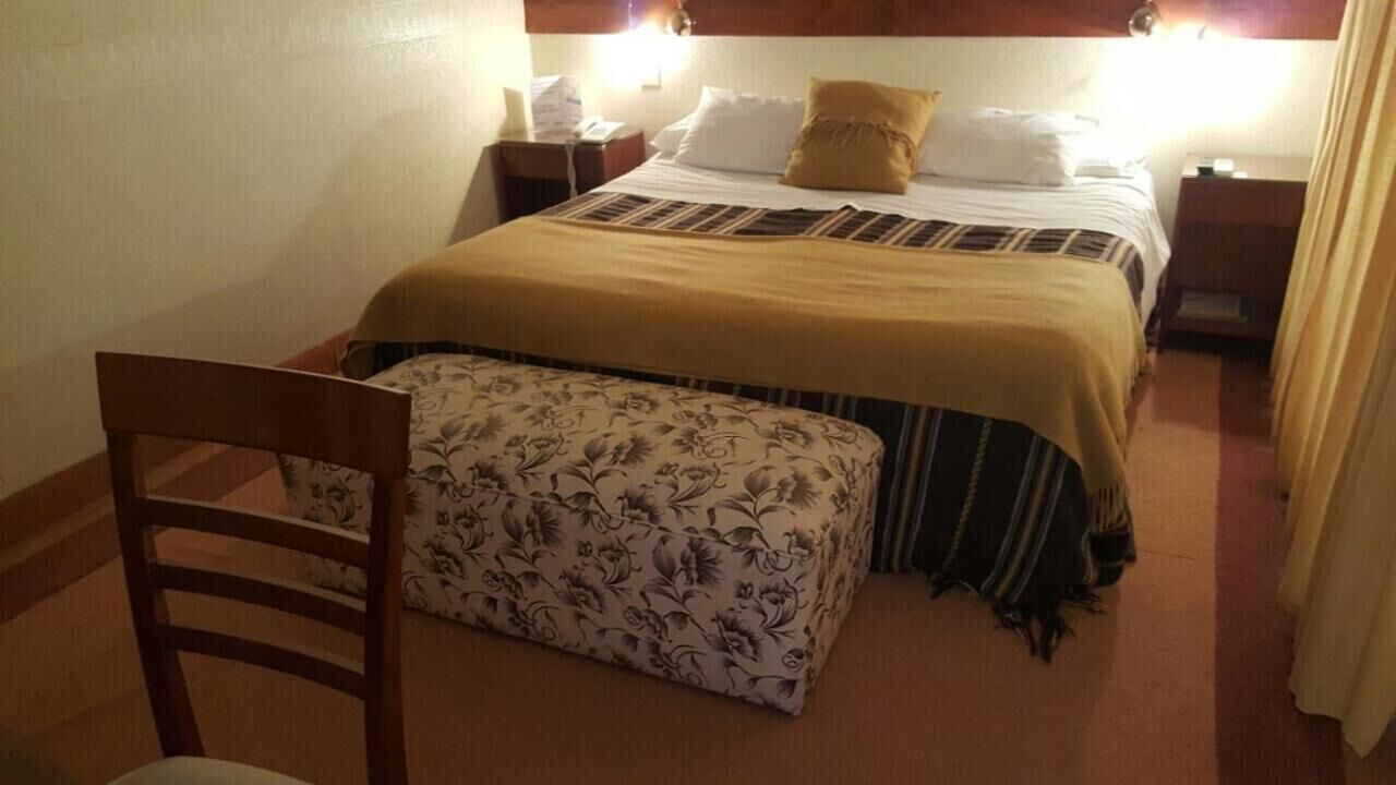 Una camera d'albergo con un letto, un comodino, una sedia e un tavolino.