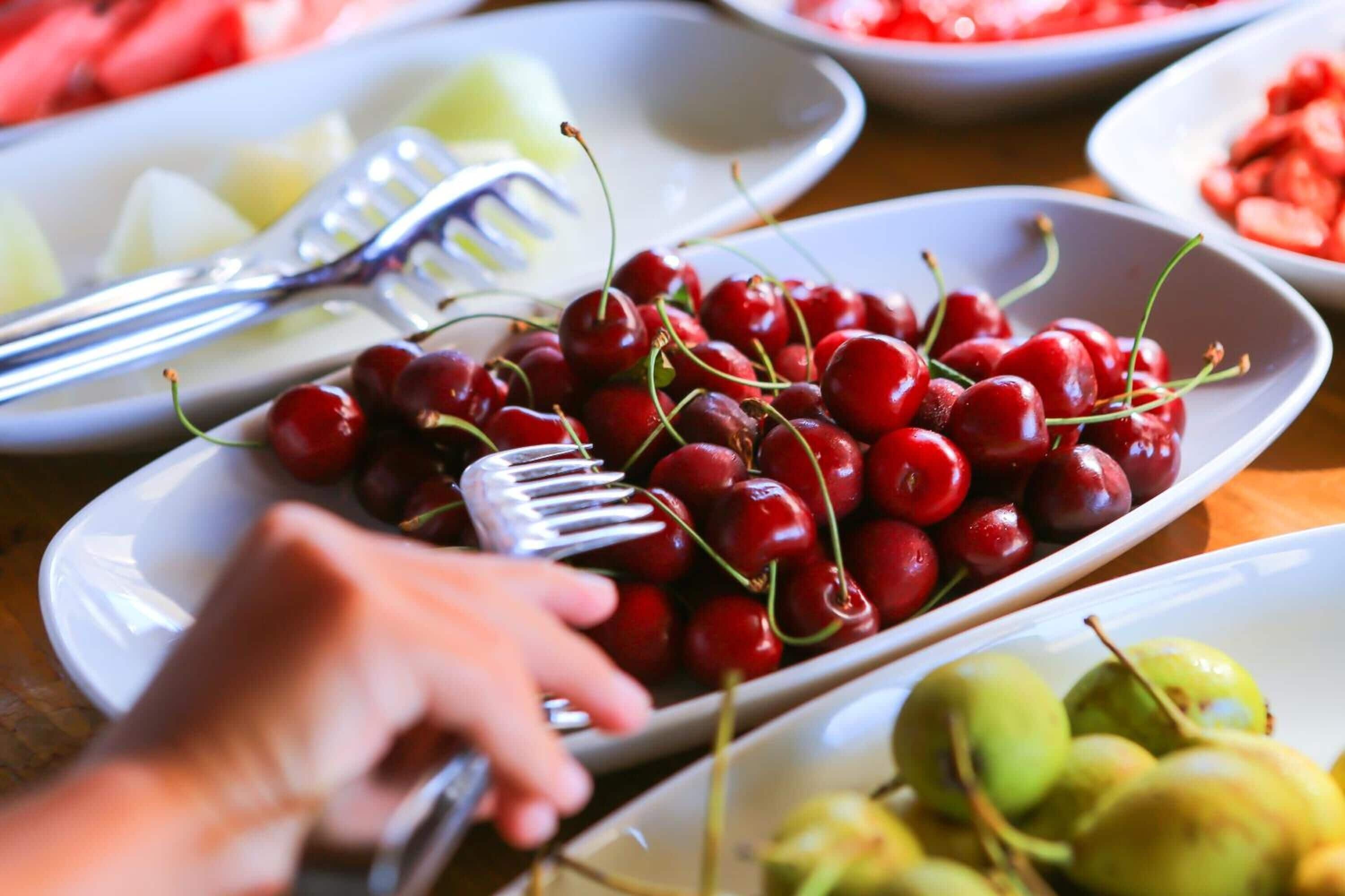 A variety of fruits on a table, including cherries, grapes, and watermelon slices.