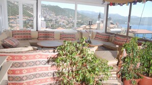 A cozy seating area with patterned cushions, a round table, and potted plants.