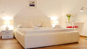 A modern bedroom with a large bed, bedside tables, a chair, and a desk. - Apartments and Rooms Bonkan Hvar  (Hvar)