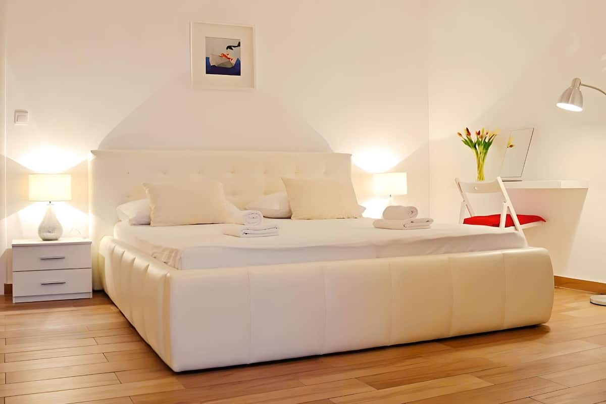 Un dormitorio moderno con una cama grande, mesitas de noche, una silla y un escritorio.