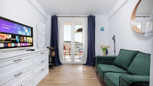 A modern living room with a flat-screen TV, white cabinets, a green sofa, and a balcony with red chairs. - Apartments and Rooms Bonkan Hvar  (Hvar)