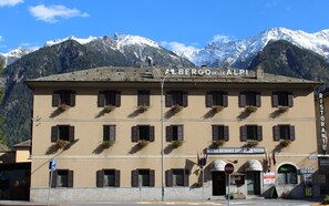 Ein Gebäude mit einem Schild, auf dem „Albergo delle Alpi“ und „Ristorante“ steht, was auf ein Hotel und Restaurant hindeutet.