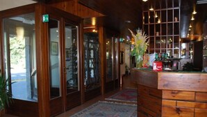 A hotel lobby with wooden paneling, a reception desk, and a view of the outside. - Hotel delle Alpi (Sondalo)