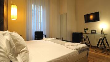 A hotel room with a large bed, a desk, a chair, a television, and a mirror.