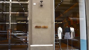 A storefront with a large glass window displaying mannequins in clothing and shoes.