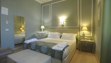 A hotel room with a large bed, bedside tables, a mirror, and a small table with a lamp.
