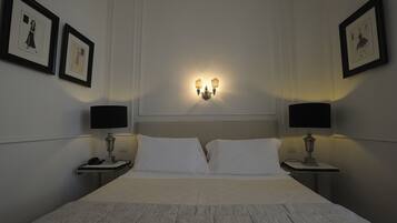 Ein Hotelzimmer mit einem großen Bett, zwei Nachttischen mit Lampen und gerahmten Bildern an den Wänden.