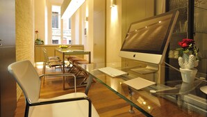 A modern office space with a glass desk, a computer, and a chair.