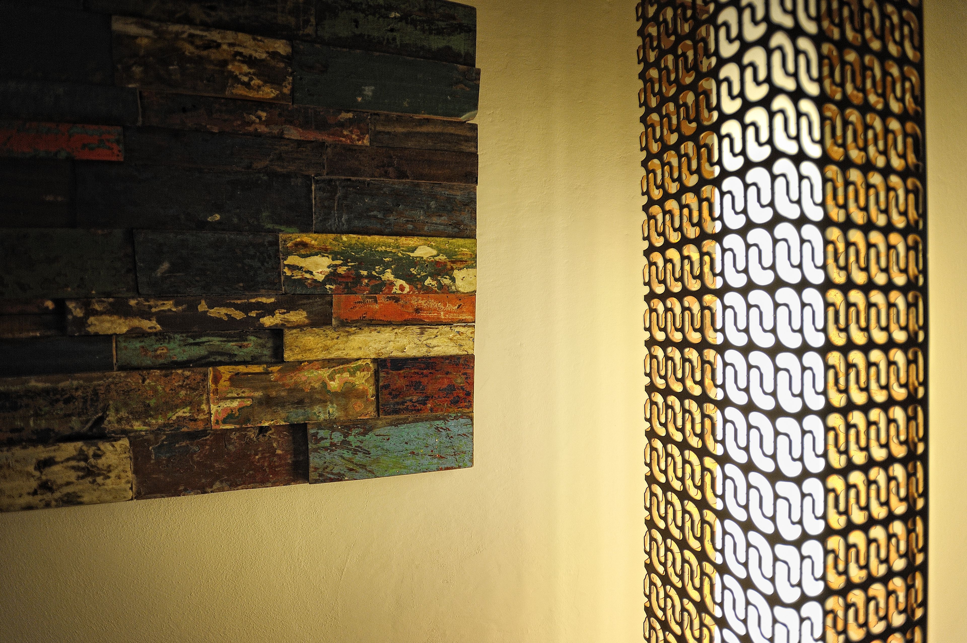 A wall with a mix of wooden planks in various colors and a patterned metal structure.