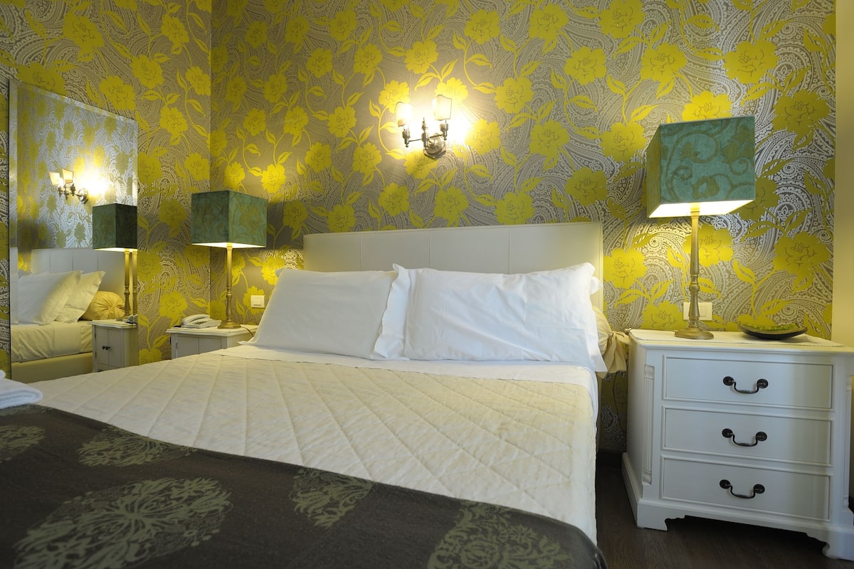 Een hotelkamer met een groot bed, twee nachtkastjes, een wandlamp en een nachtkastje.