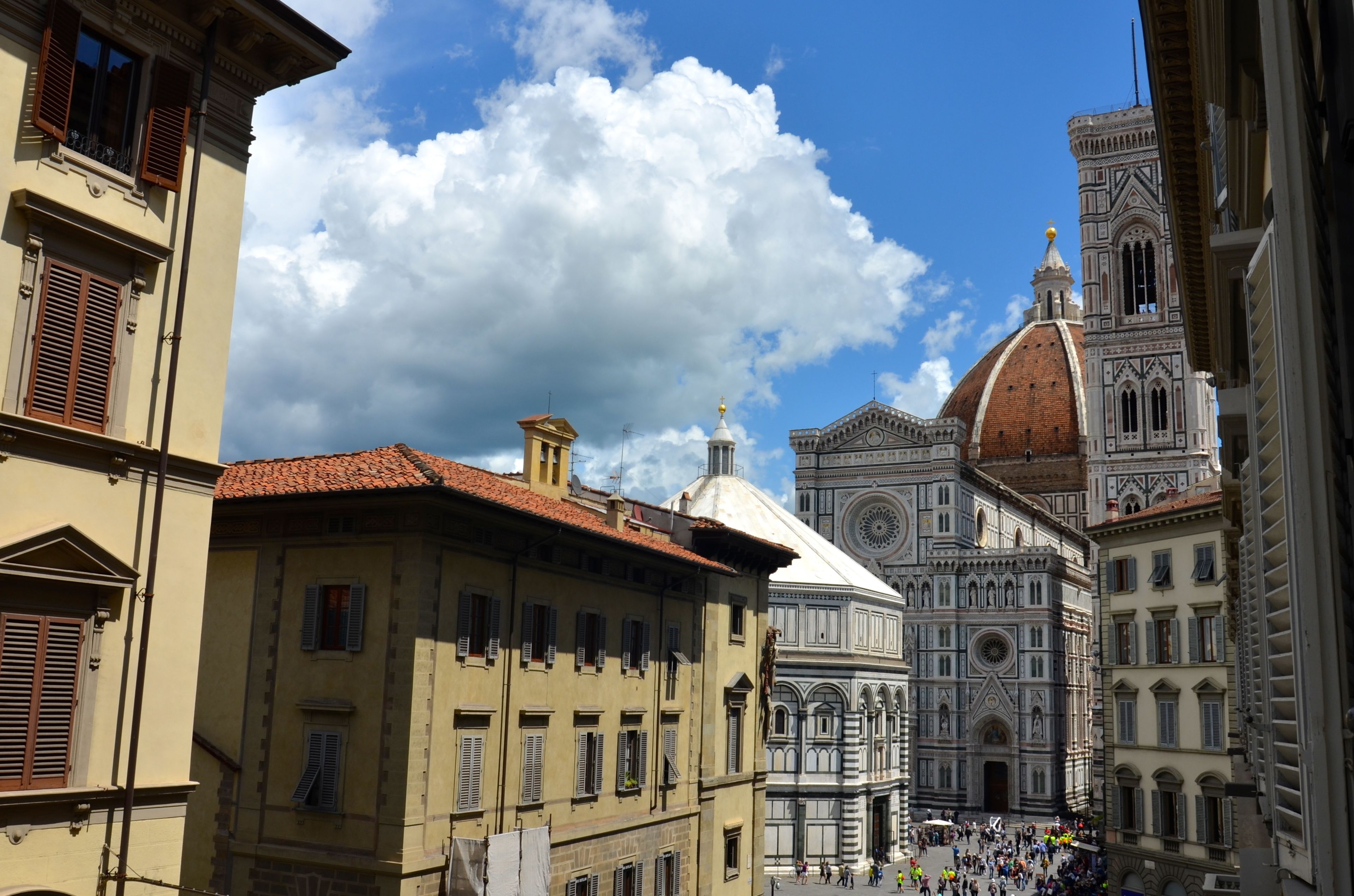 A historic building with a dome and intricate architecture, surrounded by other buildings with traditional shutters.