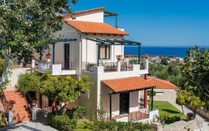 A two-story building with a red-tiled roof, a balcony, and a view of the sea. - Antilia Apts (Platanias)