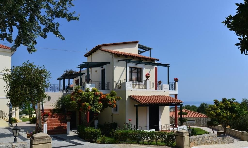 A two-story building with a balcony, a covered porch, and a view of the sea.