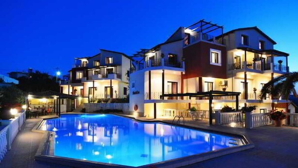 A modern two-story hotel with a swimming pool, outdoor seating, and multiple balconies. - Antilia Apts (Platanias)