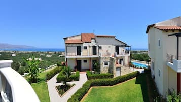 A two-story house with a balcony, a swimming pool, and a view of the sea.