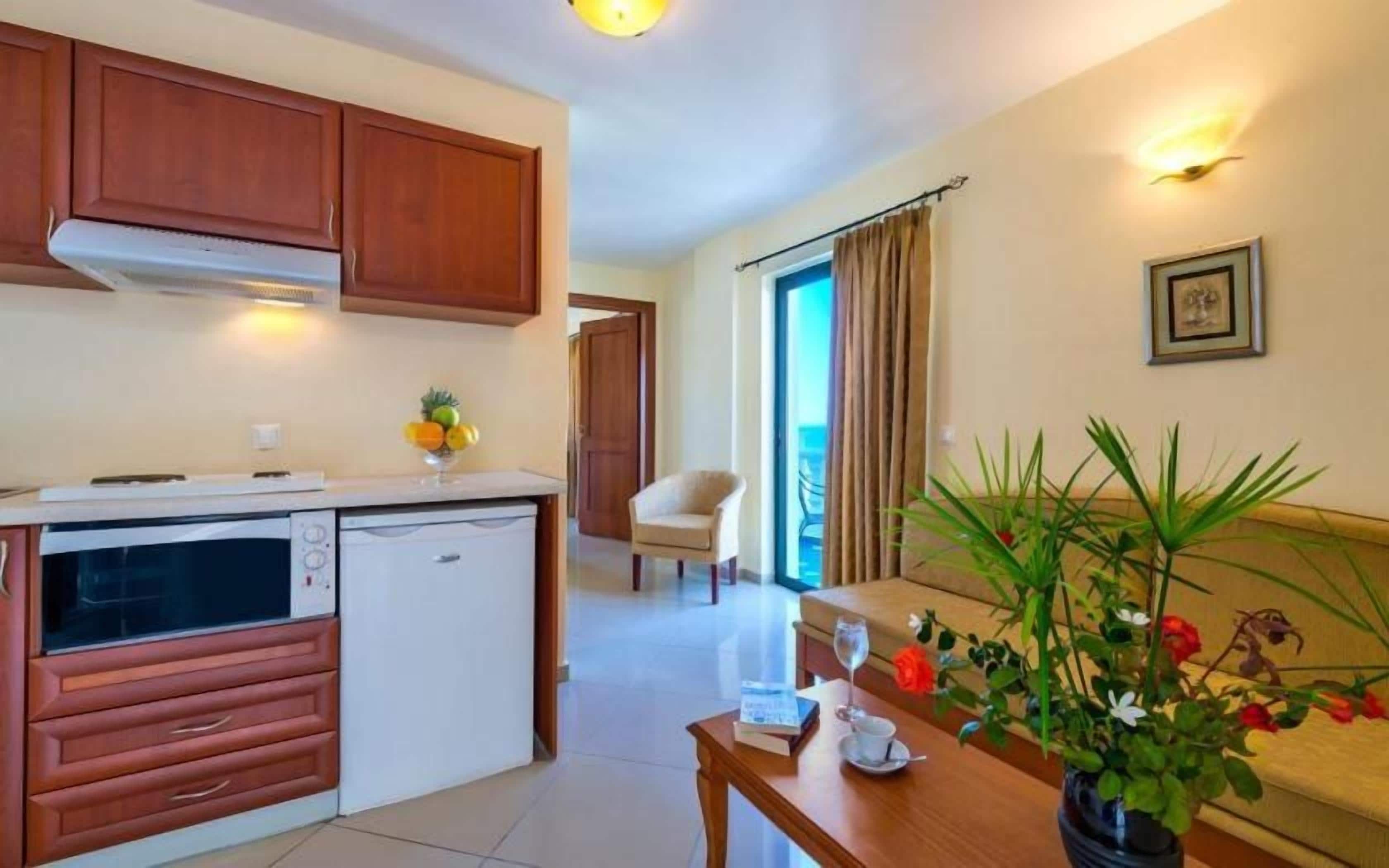 Una cocina con armarios de madera, un refrigerador y una zona de comedor con mesa y sillas.