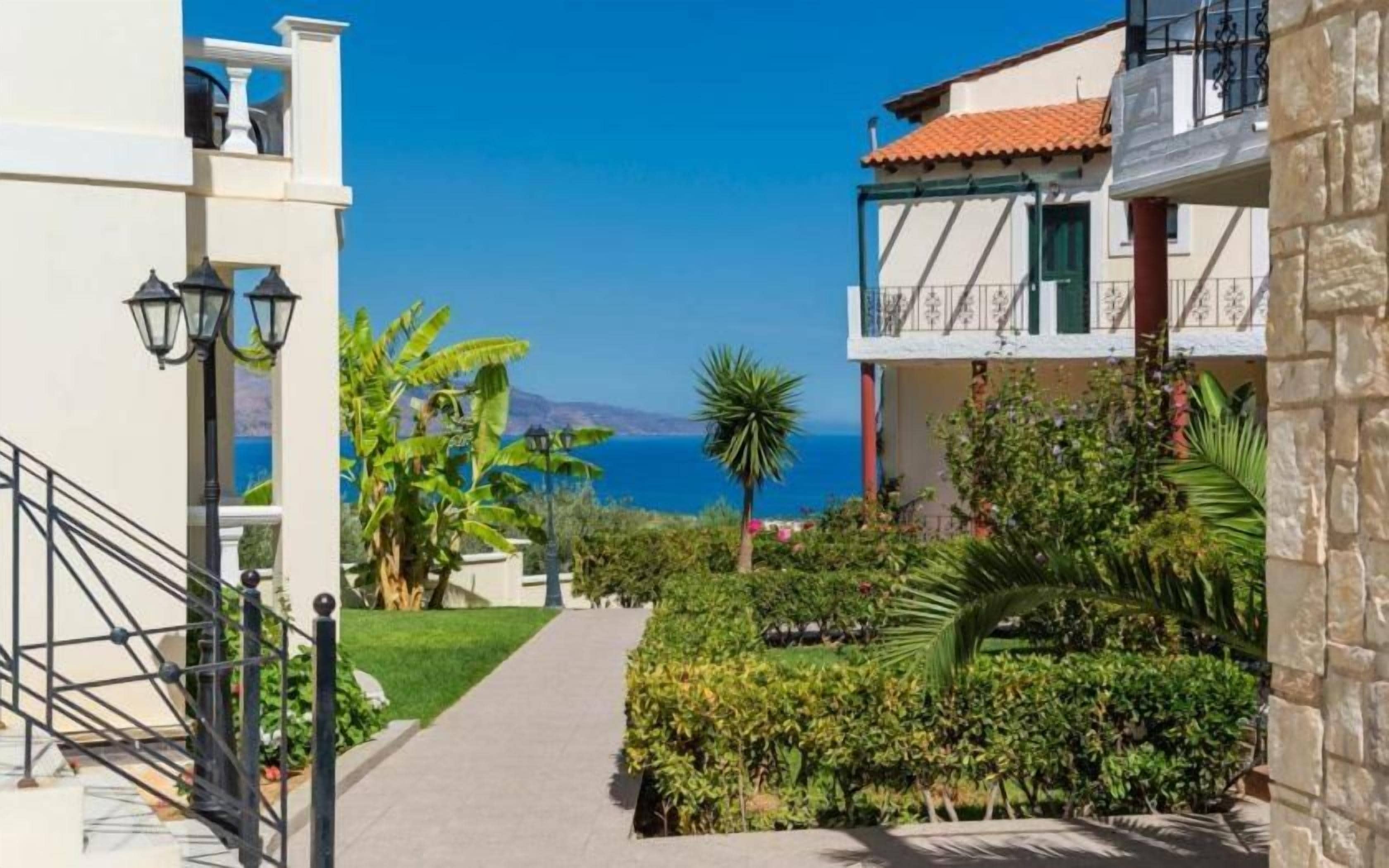 Un sendero estrecho que conduce a un edificio con balcón y vistas al mar.