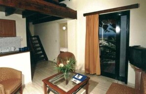 A living room with a television, a table with a plant, and a view through a glass door. - Antilia Apts (Platanias)