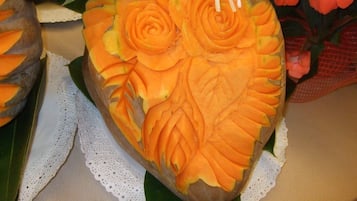 Une sculpture représentant un kaki, ornée de motifs complexes, et entourée d’éléments décoratifs tels que des fleurs et du feuillage.