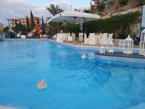 A swimming pool with a slide and lounge chairs. - Tus' Hotel (Tusa)